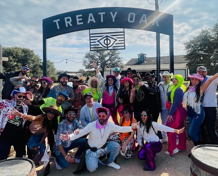 A group of people are posing for a picture in front of a sign that says treaty oak.
